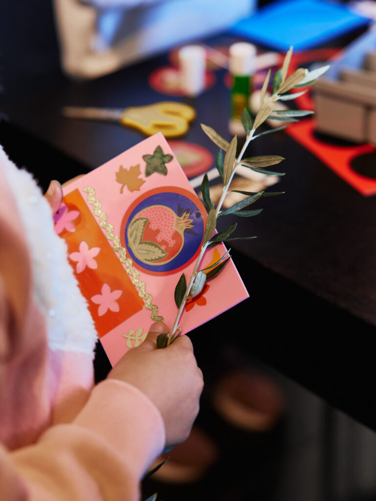 Παιδικό χεράκι που κρατά ειρεσιώνη και χριστουγεννιάτικη κάρτα